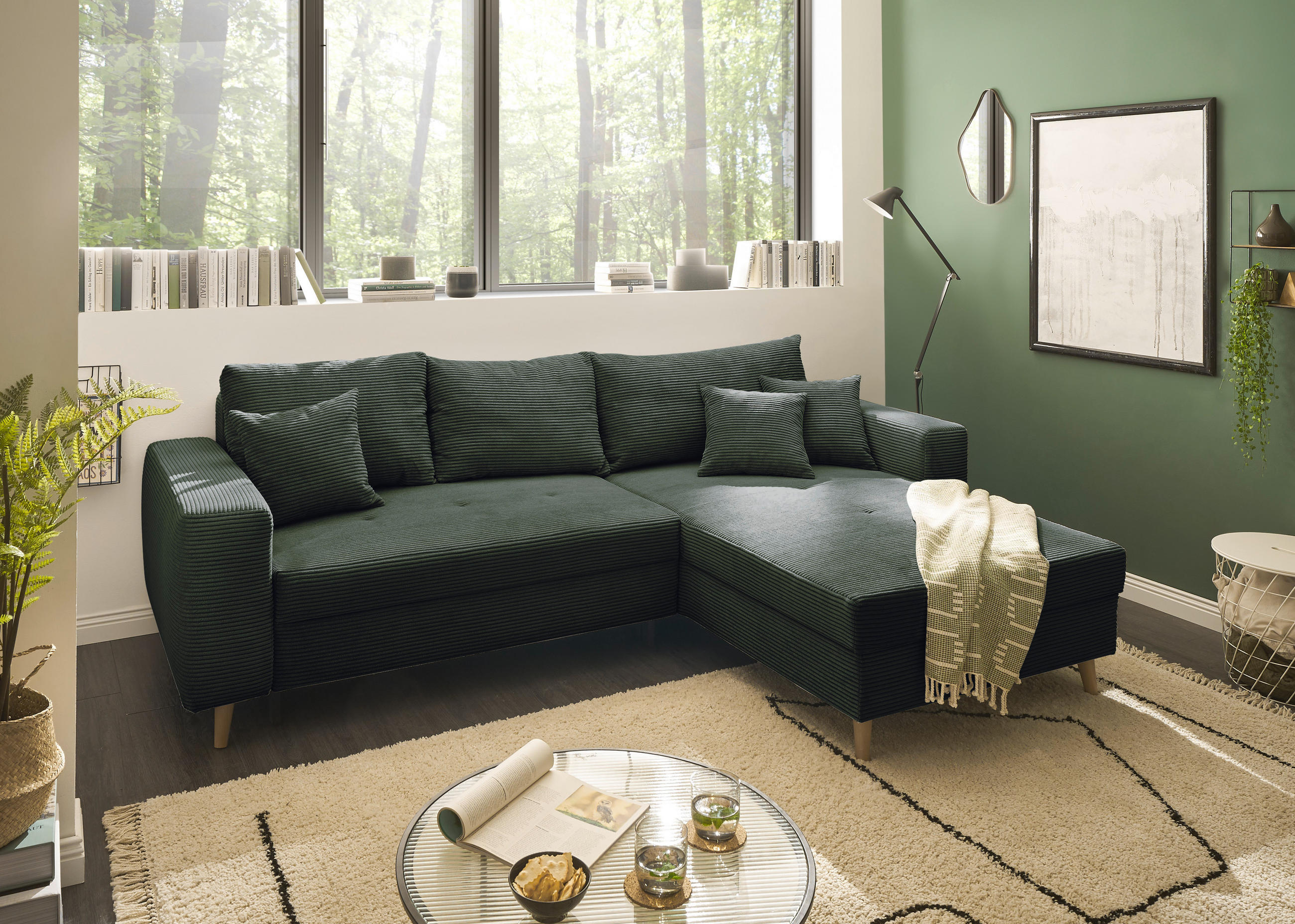 Livetastic ECKSOFA Dunkelgrün Cord, links davon: Lektüre, Blume in grün, rechts davon: Webteppich, Bild in weiß in hellem Wohnzimmer.