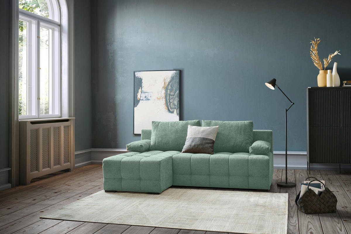 home24 ECKSOFA Dunkelgrün Chenille, links davon: Hochflorteppich, Bild, rechts davon: Stehleuchte in grün, Vase in dunklem Wohnzimmer.