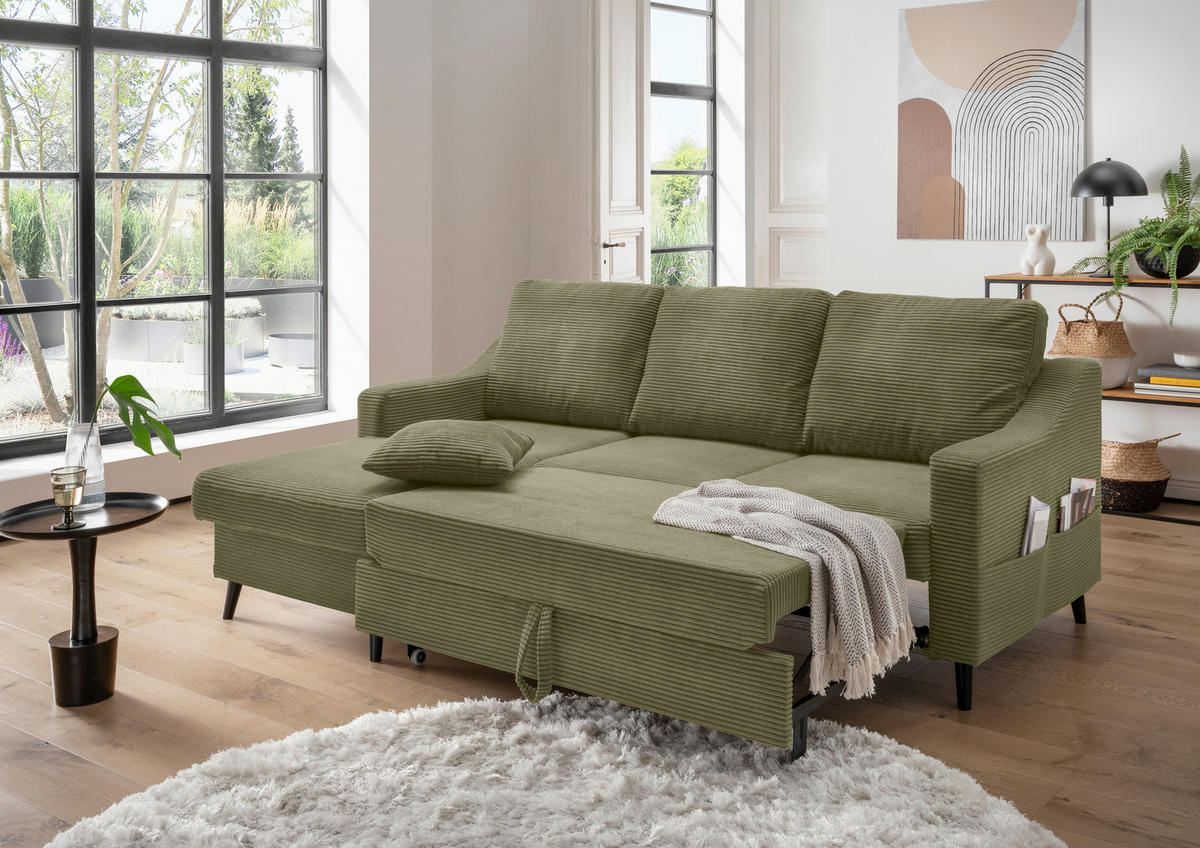 P & B ECKSOFA Olivgrün Cord, links davon: Kunstfell in weiß, Beistelltisch in braun, rechts davon: Decke, Lektüre in hellem Wohnzimmer.