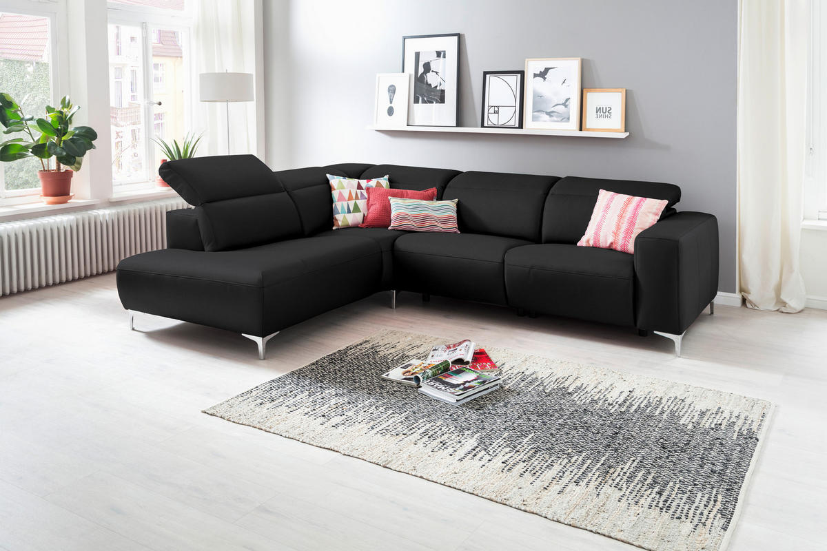 Pure Home Lifestyle ECKSOFA Schwarz Echtleder, links davon: Topfpflanze in grün, rechts davon: Hochflorteppich, Store in weiß, Kissen in hellem Wohnzimmer.
