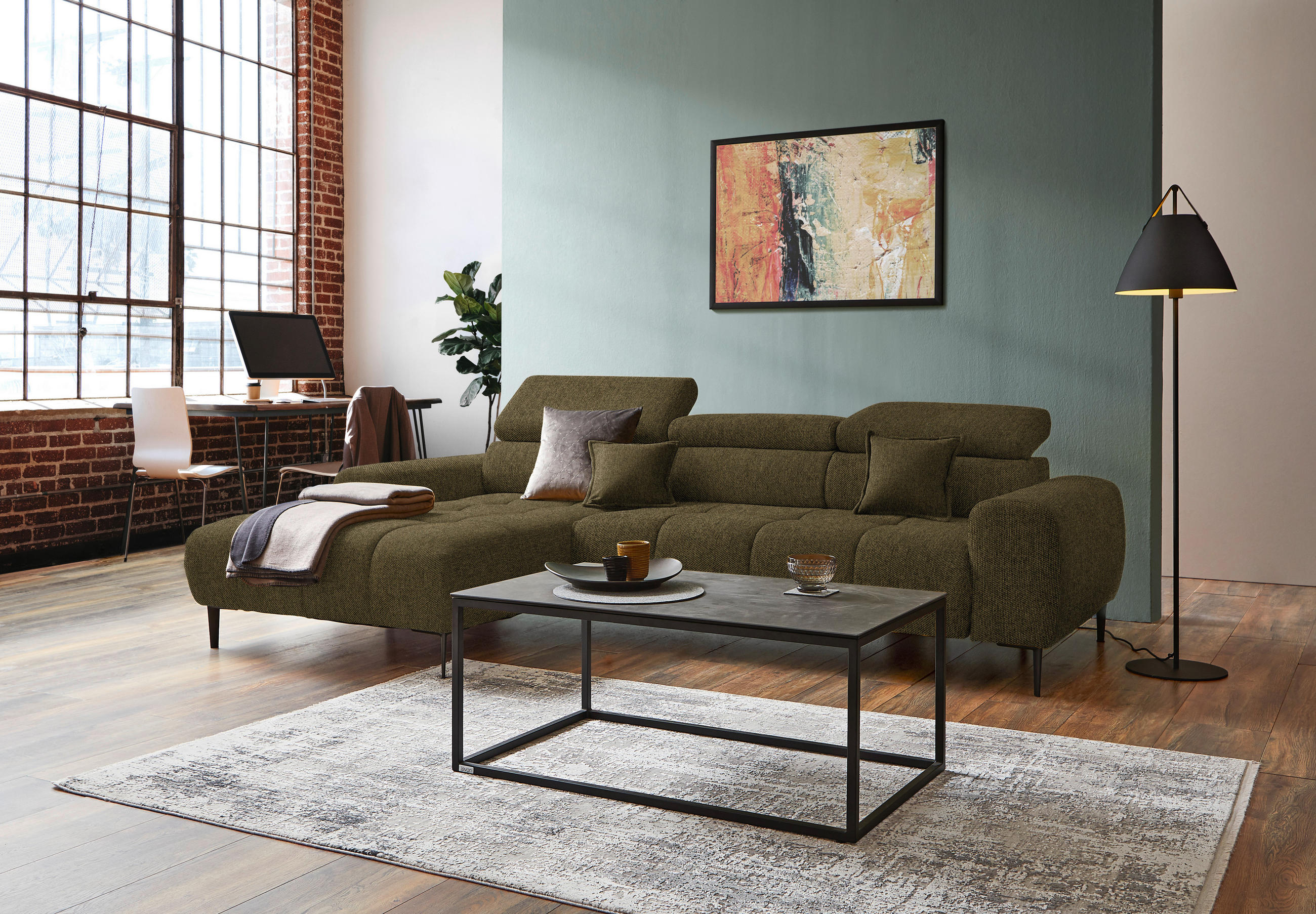 Welnova ECKSOFA Olivgrün Webstoff, links davon: Decke, rechts davon: Hochflorteppich, Couchtisch, Bild in hellem Wohnzimmer.