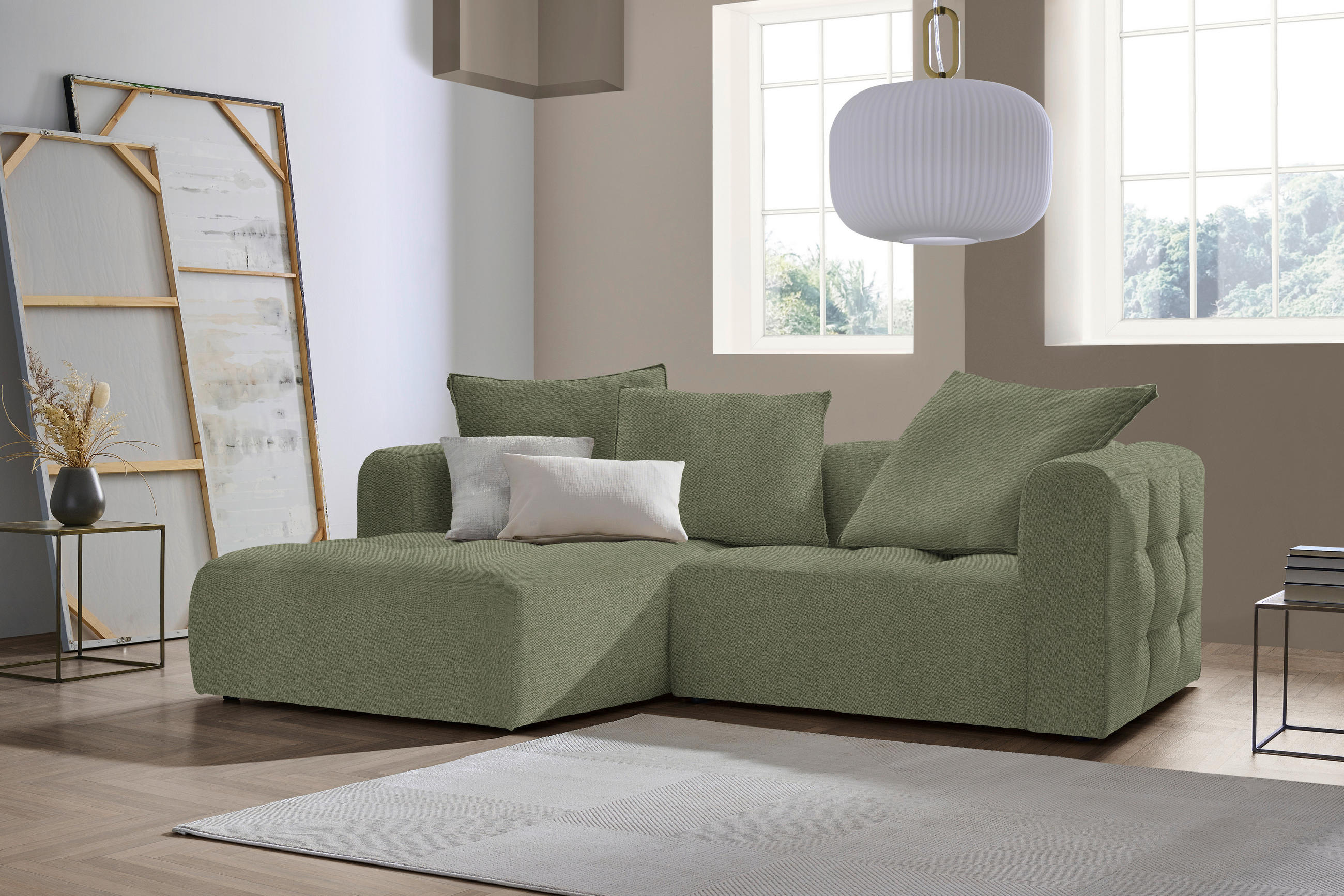 Stylife ECKSOFA MOSSO Grün Flachgewebe, links davon: Beistelltisch, rechts davon: Hochflorteppich in weiß, Deckenbeleuchtung, Store in weiß in hellem Wohnzimmer.