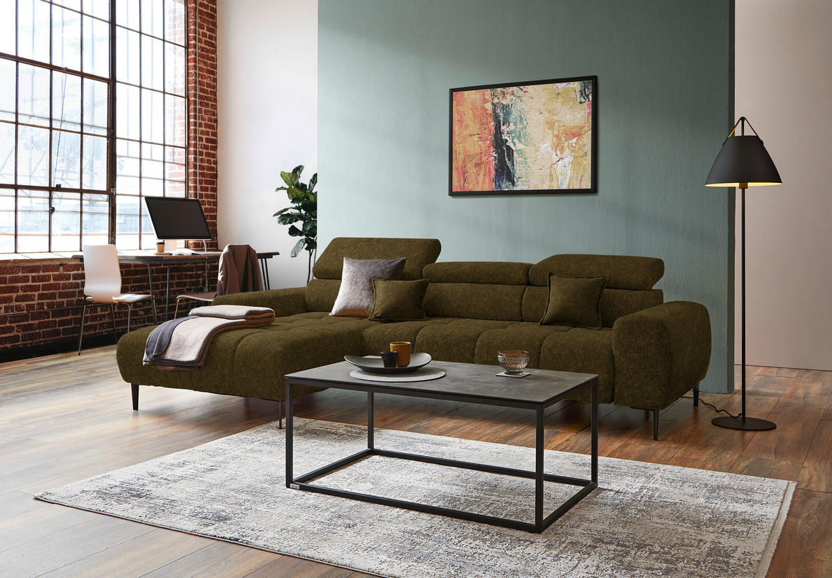 Welnova ECKSOFA Olivgrün Samt, Webstoff, links davon: Hochflorteppich, Decke, rechts davon: Couchtisch, Bild in hellem Wohnzimmer.
