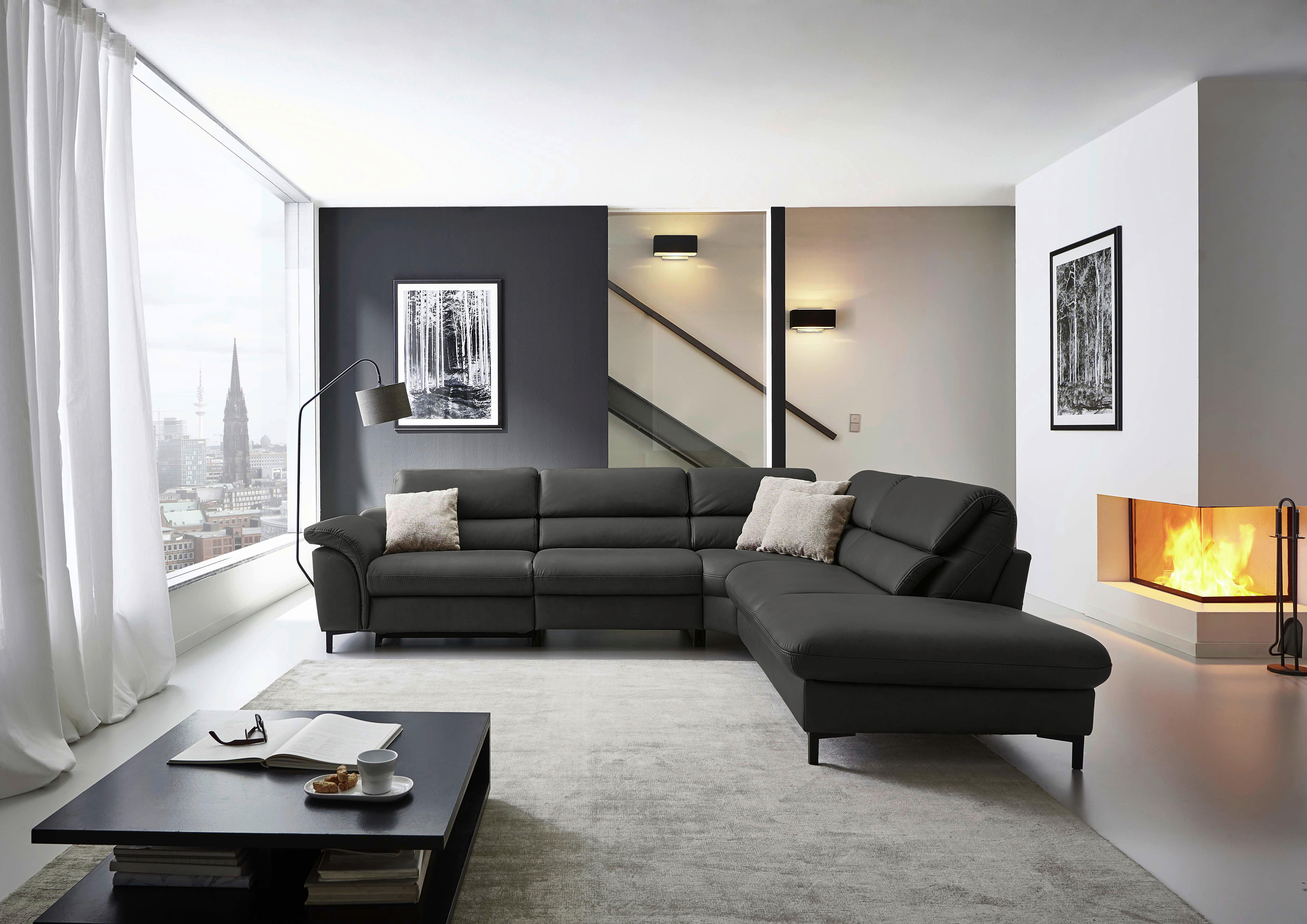 Hukla ECKSOFA Valdera Schwarz Echtleder, links davon: Hochflorteppich, Couchtisch in schwarz, Gardine in weiß, Lektüre in hellem Wohnzimmer.