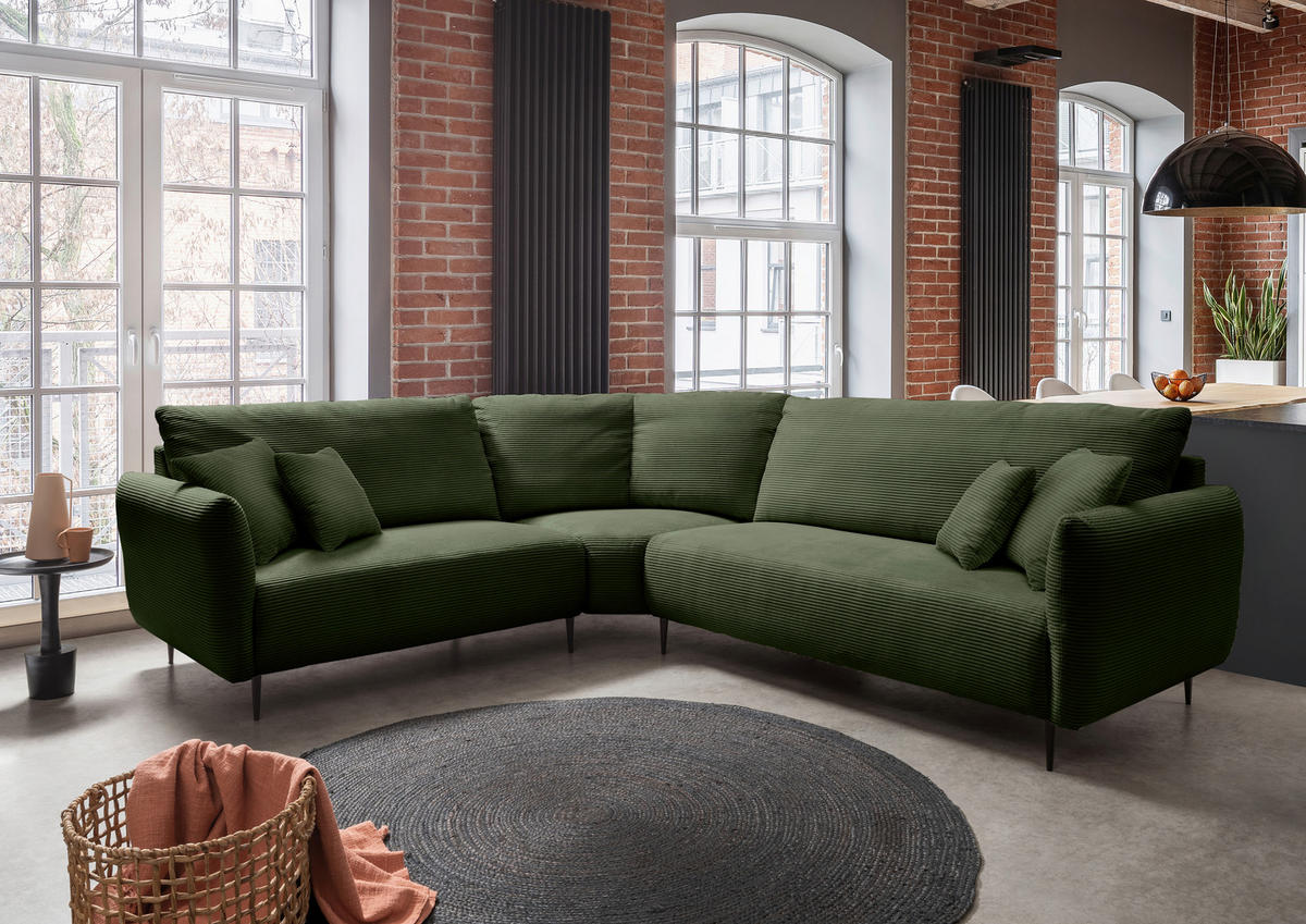 Livetastic ECKSOFA Dunkelgrün Cord, links davon: Hochflorteppich, Beistelltisch, rechts davon: Deckenbeleuchtung, Gardine in dunklem Wohnzimmer.