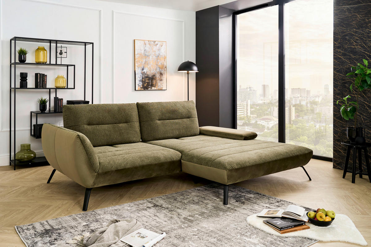 Carryhome ECKSOFA Olivgrün Webstoff, links davon: Webteppich, Regal, rechts davon: Bild, Deckenbeleuchtung in hellem Wohnzimmer.