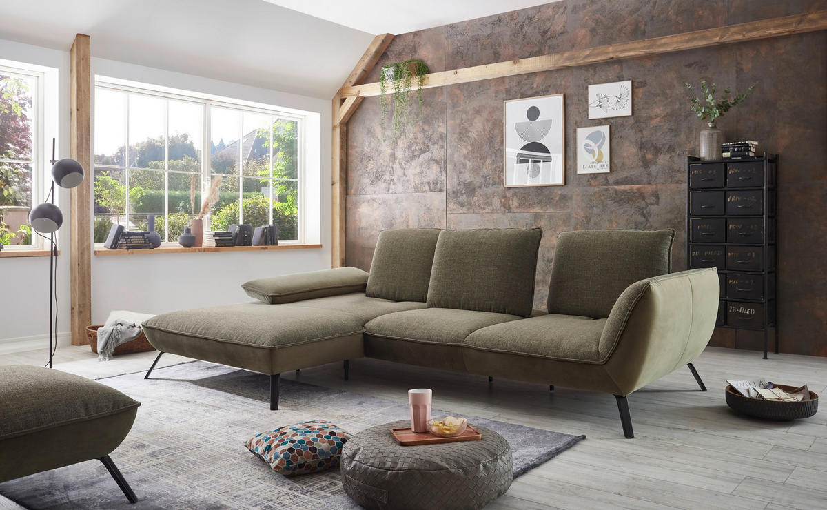 Moderano ECKSOFA Olivgrün Flachgewebe, links davon: Hochflorteppich, Kissen, rechts davon: Highboard, Lektüre in hellem Wohnzimmer.