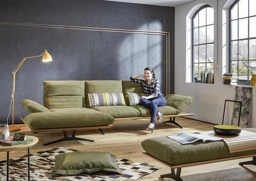 Dieter Knoll ECKSOFA Grün Flachgewebe, links davon: Kunstfell in grün, Kissen in grün, rechts davon: Sitzbank in grün, Lektüre in weiß in hellem Wohnzimmer.