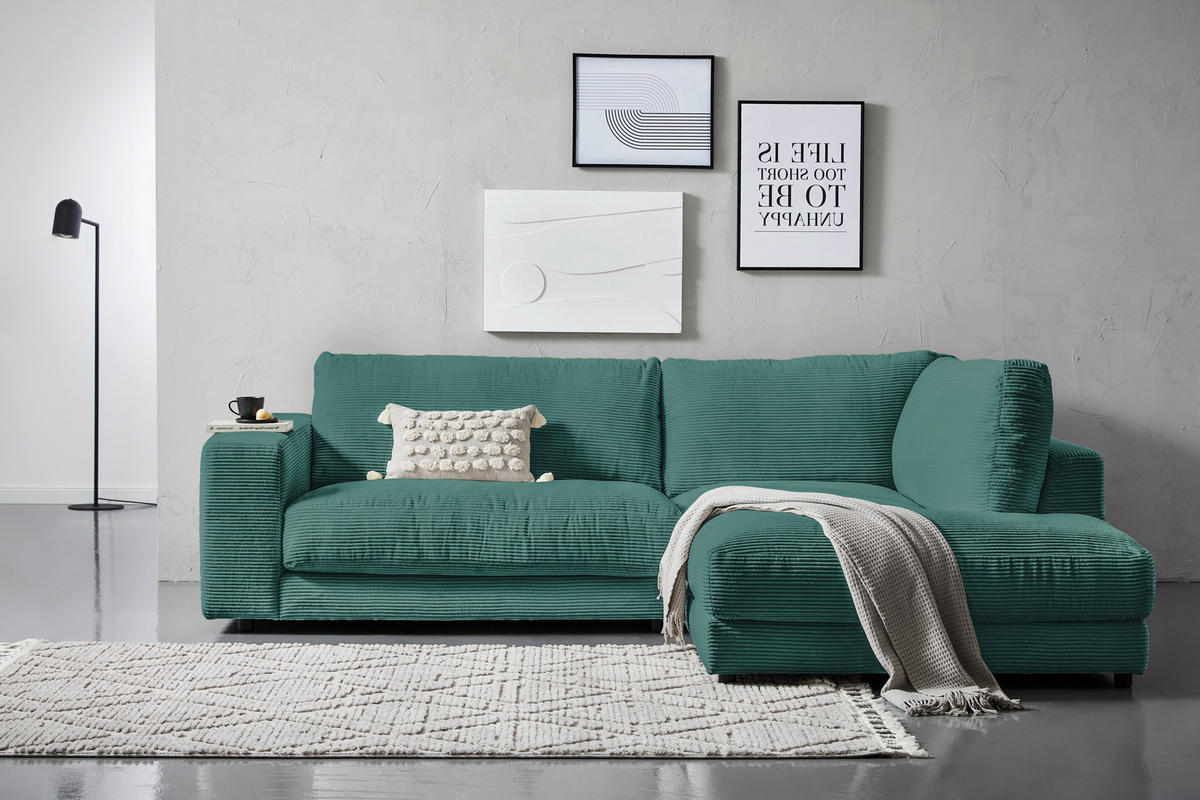 Hom`in ECKSOFA Grün Cord, links davon: Läufer, rechts davon: Decke in grün, Bild in hellem Wohnzimmer.