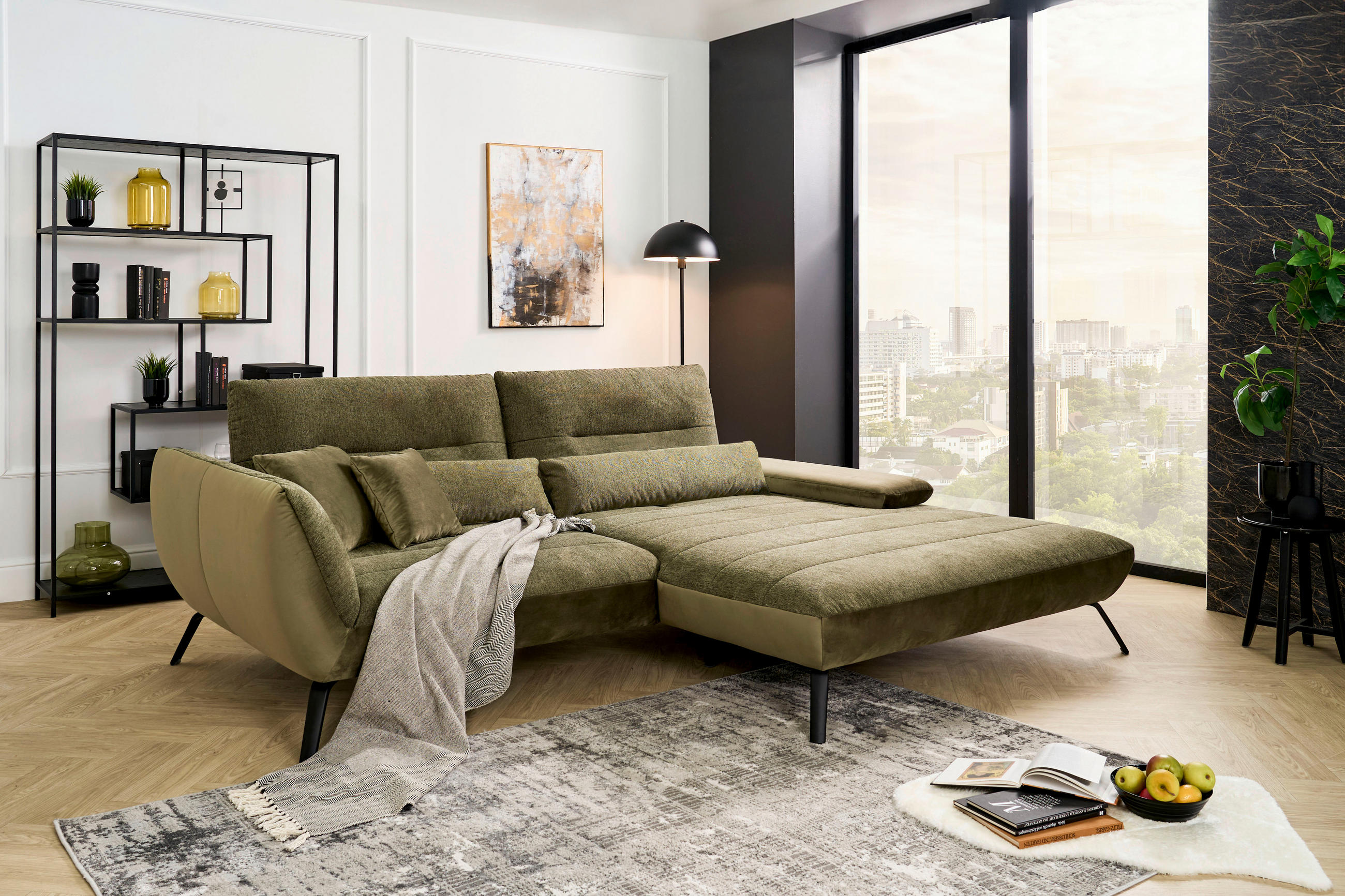 Carryhome ECKSOFA Olivgrün Webstoff, links davon: Webteppich, Decke, Regal in grün, Kissen in grün in hellem Wohnzimmer.